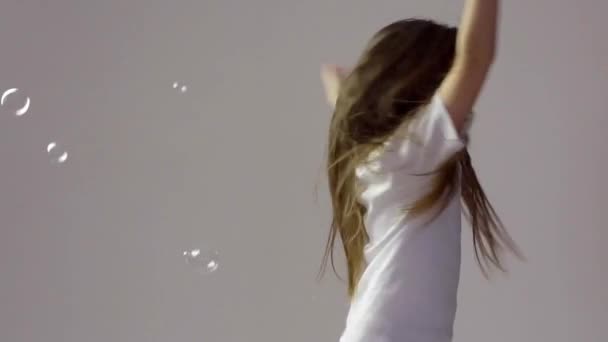 Маленька дівчинка дме мильні бульбашки — стокове відео