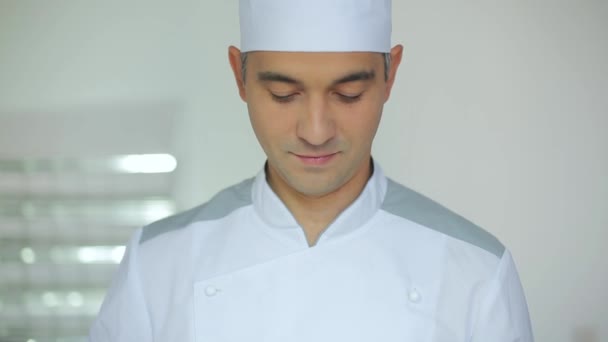 Manlig kock i ett kommersiellt kök står på den vita bakgrunden — Stockvideo