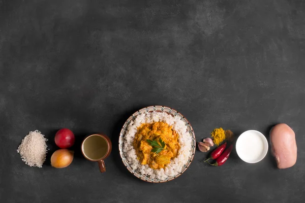 Chicken curry with rice and ingredients on the black chalkboard. Top view  copy space. Horizontal orientation — Stock Photo, Image