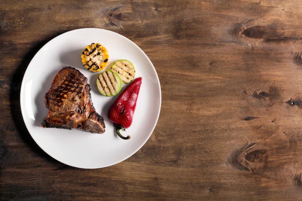 Sebze ile kahverengi ahşap zemin üzerinde ızgara biftek — Stok fotoğraf