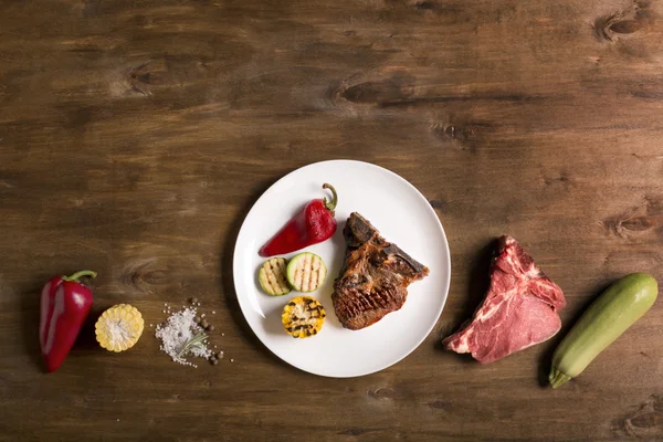 Gegrilltes Steak auf braunem Holzhintergrund mit Gemüse — Stockfoto
