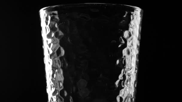 Вода выливается в прозрачное стекло на черном фоне — стоковое видео