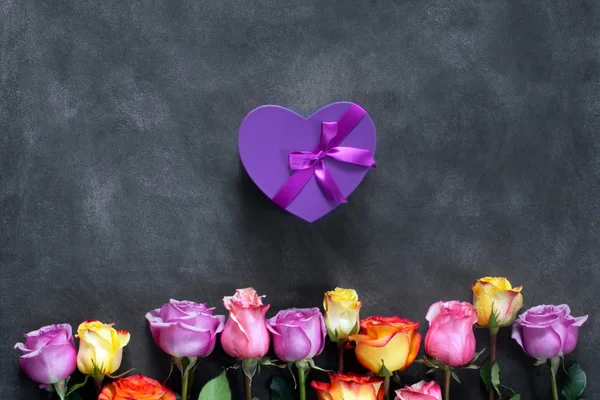 Фиолетовые и желтые розы, коробка присутствует на черном фоне — стоковое фото