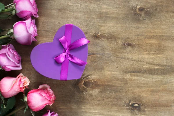 Purple and yellow roses, box present on wooden background