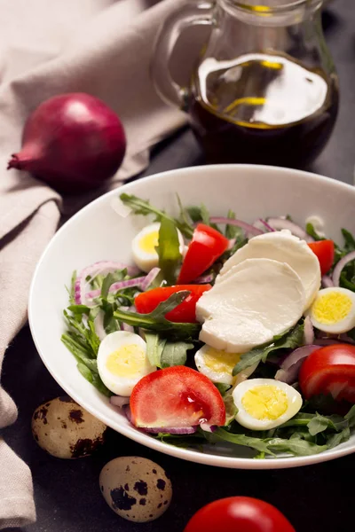 Italian salad prepared with arugula, mozzarella, eggs. Black background — Stock Photo, Image