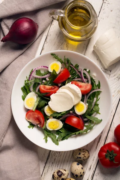 Insalata italiana preparata con rucola, mozzarella, uova. sfondo in legno bianco — Foto Stock