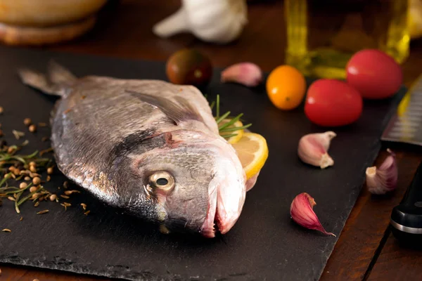 Mittelmeerfisch - Dorado und Gemüse auf der Tafel. Seitenansicht — Stockfoto