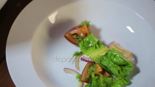 Voorbereiding van frisse salade met groene bladeren, ui en tomaten — Stockvideo