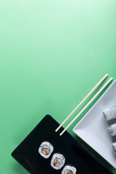 Ιαπωνική Σούσι σε πράσινο φόντο. Ρολά και chopsticks. Κατακόρυφο προσανατολισμό — Φωτογραφία Αρχείου