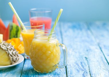 Mavi ahşap rustik arka plan üzerinde üç bardak taze ananas ve karpuz smoothie