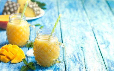 Torquise ahşap rustik arka plan üzerinde meyve ile iki bardak taze ananas ve mango smoothie