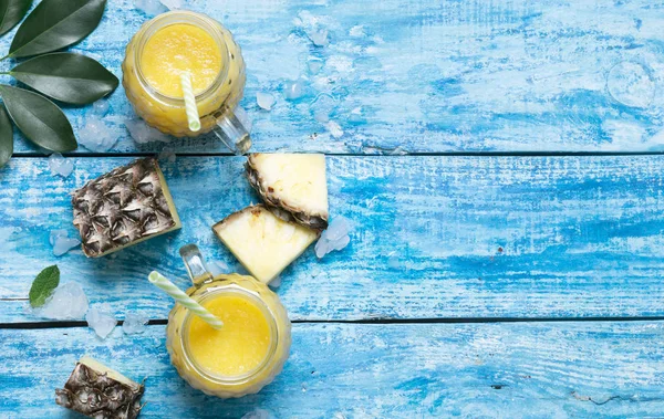 Verse ananas smoothie in glazen met rietjes op een blauwe houten rustieke achtergrond — Stockfoto