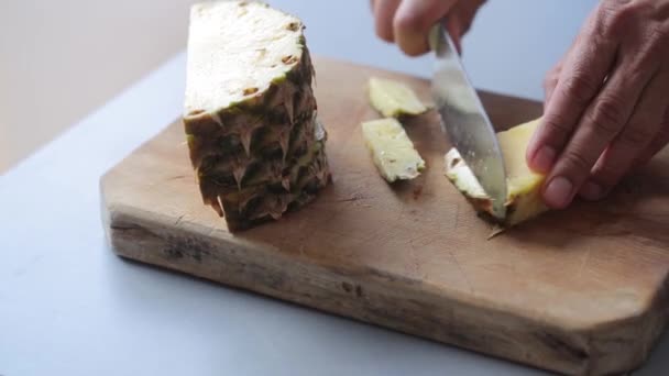 Chef hands peel pineapple on wooden cutting board — Stock Video