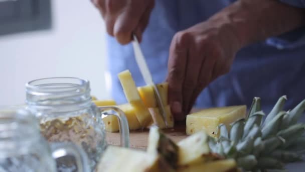 Τα χέρια του σεφ κόβετε ένα ανανά σε ξύλο κοπής. Ο άνθρωπος προετοιμασία φρούτα επιδορπίων — Αρχείο Βίντεο