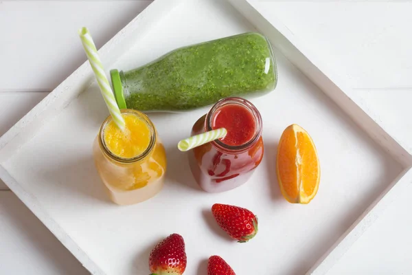 빨 대에 과일과 야채 흰색 목조 소박한 배경으로 병에서 신선한 딸기, 오렌지, 브로콜리 스무디 — 스톡 사진