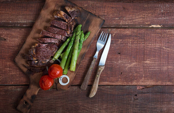 Grilled beef steak with vegetables on a wooden rustic background, with copy space