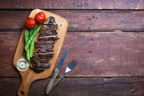 Bife grelhado em uma placa de cozinha e fundo rústico de madeira — Fotografia de Stock