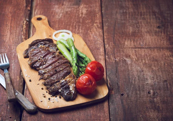 Steak de boeuf grillé avec asparaguas et tomates sur fond rustique en bois — Photo