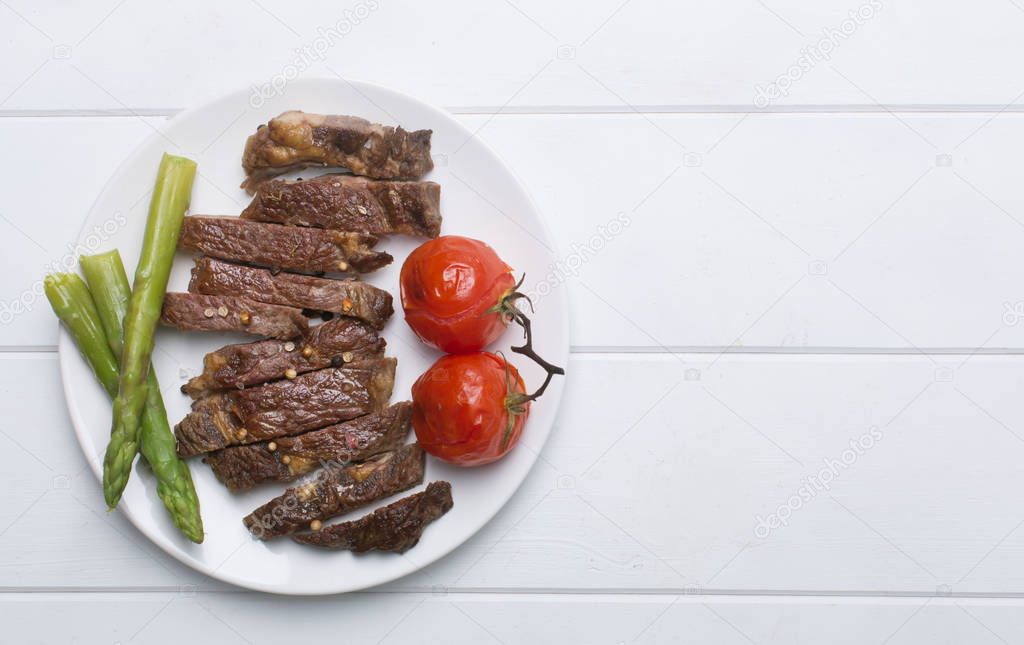 Grilled beef steak on a white plate and white background, flat lay and copy space
