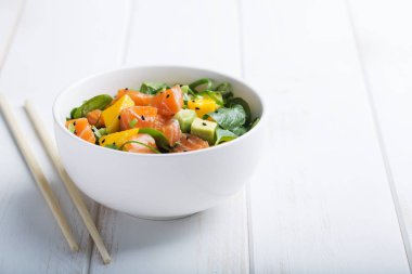 Hawaiian Poke salata somon, avokado ve kopya alanı, sebze ve yemek çubukları ile bir beyaz ahşap rustik arka planda bir kase sebze. Yatay