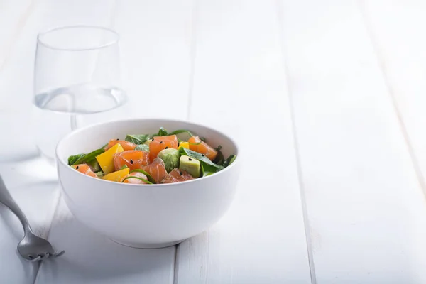 Hawaiianischer Poke Salat mit Lachs, Avocado und Gemüse in einer Schüssel auf weißem rustikalen Holzgrund mit Kopierraum, Gemüse und einer Gabel — Stockfoto