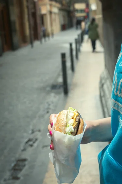 Стильная хипстерша, ставящая голубой, держит в руках гамбургер. Лето — стоковое фото