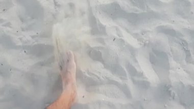 Pantolon giymiş erkek bacakları Akdeniz kıyısında kumda yürüyor, 4K video.