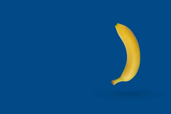 Yellow banana on a blue background with copy space. Classic color combination for 2020 — Stock Photo, Image