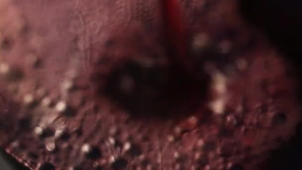 Einschenken von Rotwein in ein Glas auf dem dunklen festlichen Hintergrund mit buntem Bokeh, Nahaufnahme — Stockvideo