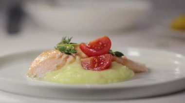 Pişiren el, bir parça kırmızı balık somonuyla patates püresi ve kekik ile süslenmiş.