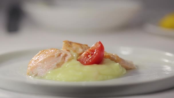 Köchin legt ein Stück rote Tomate auf einen Teller mit Kartoffelpüree und dekoriert es mit Thymian — Stockvideo