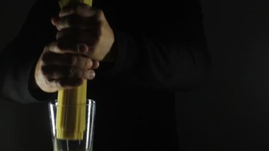 Adam koyu siyah arka planda altın renginde çiğ makarna tutuyor.
