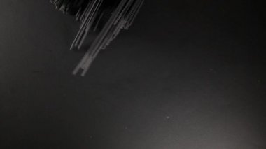 Adam mürekkep balığı spagettisini koyu siyah arka plana koyar, videoyu kapatır.