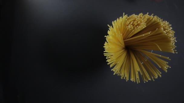 Man houdt gouden kleur rauwe spaghetti pasta op de donkere zwarte achtergrond — Stockvideo