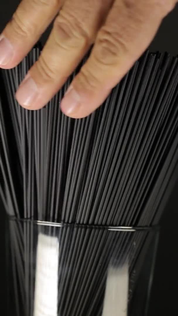 L'homme touche l'encre de seiche spaghetti pâtes sur le fond noir foncé, fermer la vidéo verticale — Video