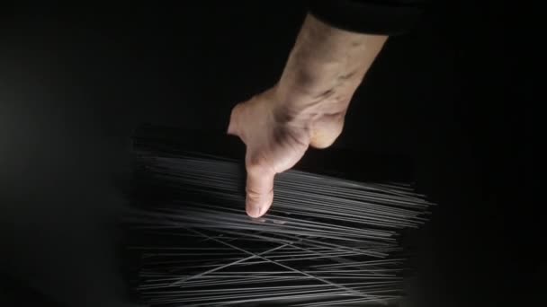 Man puts cuttlefish ink spaghetti pasta on the dark black background, close up video — ストック動画