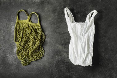 A green string bag and a white plastic bag on a black background