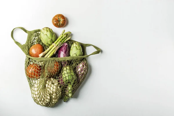 Verduras frescas en una bolsa de hilo verde sobre un fondo blanco. Ca —  Fotos de Stock