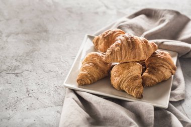 Kare bir tabakta taze pişmiş Fransız kruvasanı.