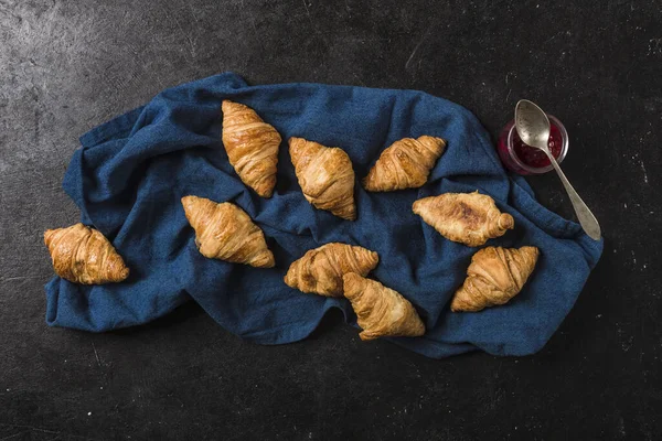 Freshly baked French croissants with a jar of jam on a black bac — 스톡 사진