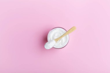 Collagen in a glass with a wooden spoon on a pink background clipart