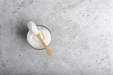 Yakın plan kolajeni bir kaşıkla bardakta beton arka planda..