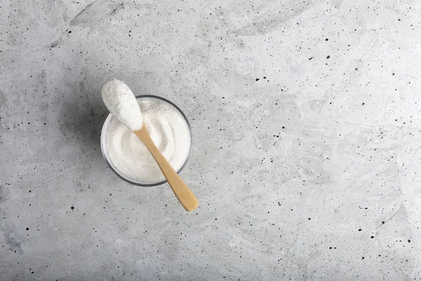 Colágeno de primer plano en un vaso con una cuchara, sobre fondo de hormigón . — Foto de Stock