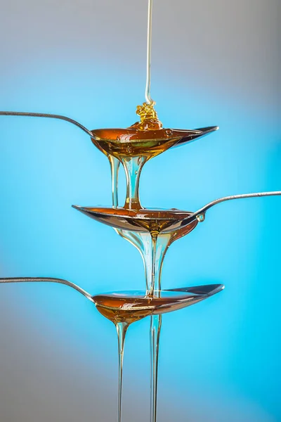 Goldener süßer Honig schwappt über bunten Hintergrund — Stockfoto