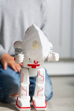 Çocuk oyuncaklarıyla oynuyor, Coronavirus koruma maskesi ve robot gibi.