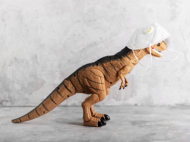Dinozor oyuncağı koronavirüs koruma maskesi takıyor, yatay tıbbi konsept