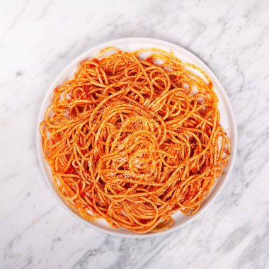 Domates soslu makarna ve modern tabakta beyaz arka planda fesleğenli kiraz domatesleri.