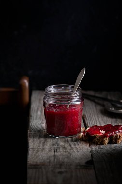 Kavanozda ahududu reçeli ve siyah bir arka planda sandviç.