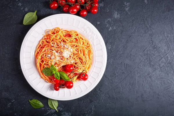 stock image Pasta with tomato sauce and cherry tomatoes with basil on a dark background. Copy space. Fresh or dry spaghetti is cooked in a large pot with salted boiling water, and then dried in a colander