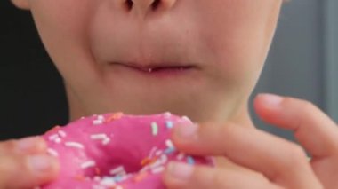 Çocuk pembe parlak çöreği ısırıp çiğniyor, komik bir video.